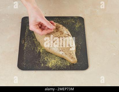 Pane di segale seminato, cospargere i semi di cumino sull'impasto Foto Stock