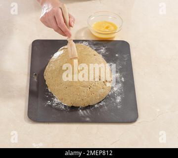 Pane artigianale di segale, spazzolando la glassa d'uovo sulla pagnotta Foto Stock