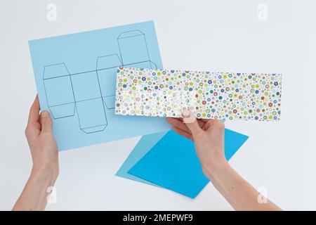 Tenendo la scheda colorata sopra il modello della scatola, primo piano Foto Stock