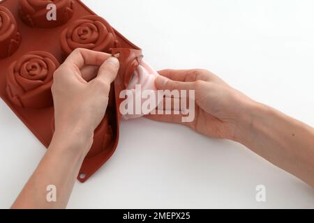 Rimuovere delicatamente il sapone rosa opaco del set staccando la muffa posteriore, primo piano Foto Stock