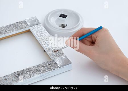 Applicazione di vernice nera e lavaggio ad acqua alla calotta del mosaico sulla cornice dell'immagine per creare un effetto chiazzato, primo piano Foto Stock