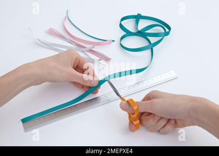 Utilizzando le forbici per tagliare strisce di nastro per tessitura, primo piano Foto Stock