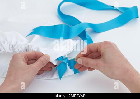 Inserimento del nastro blu attraverso l'alloggiamento della borsa per scarpe utilizzando il perno di sicurezza, primo piano Foto Stock