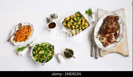 Gamba arrosto di agnello e patate novelle al crescione, stir-fried verdure di primavera e porri, arrosto carotine, il sugo di carne, salsa alla menta, posate, bicchiere di vino e i tovaglioli, steso sul tavolo Foto Stock