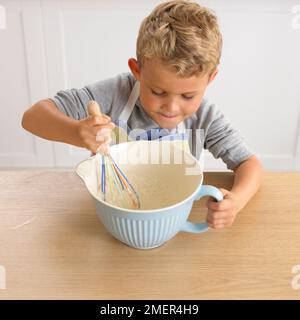 Ragazzo frustando frittella miscela, 4 anni Foto Stock