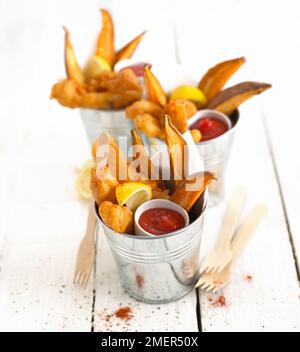 Pesce e fette di patate dolci al forno in pentole servite con salsa di pomodoro Foto Stock