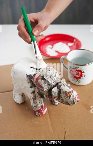 Fare una papier-mache orso polare piggy banca utilizzando la vecchia bottiglia di latte, pittura con vernice acrilica bianca Foto Stock