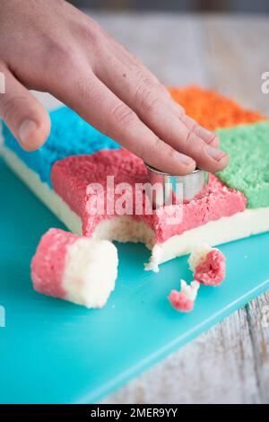 Usando un piccolo taglierino rotondo per tagliare i pezzi dal blocco di miscela di cocco, facendo i morsi di cocco Foto Stock