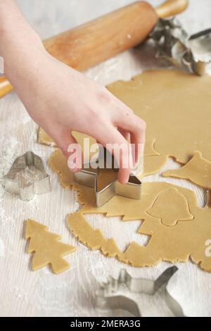 Taglio dell'albero di Natale e delle forme delle stelle dalla pasta di pan di zenzero Foto Stock