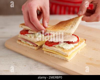 Aggiungere una terza fetta di pane bianco tostato sul panino del club Foto Stock