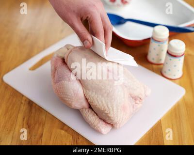 Arrosto di pollo, asciugando la pelle di pollo intero crudo con carta da cucina Foto Stock