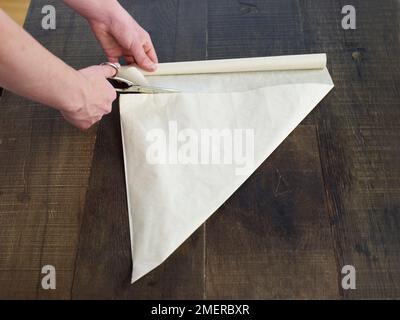 Pan di zenzero, tagliando carta da forno bianca in triangoli Foto Stock