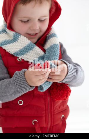 Ragazzo che indossa una doratura con cappuccio e sciarpa lanosa, 2 anni Foto Stock