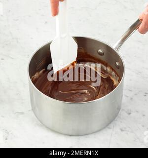 Mescolando la glassa di cioccolato in pentola, facendo ganache di cioccolato Foto Stock