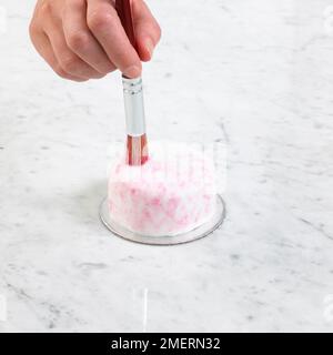 Torta ricoperta di glassa morbida condente decorata da dabbing cibo colorante con pennello da cucciolo Foto Stock