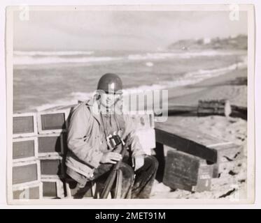 Coast Guardsman trova un momento di riposo. Il fotografo di combattimento della Guardia Costiera William Forsythe, ex fotografo del giornale Washington D.C., riposa per un secondo sulla spiaggia di Gela, Sicilia, prima di tornare alla sua nave. Coast Guardsman Forsythe fu tra i primi ad atterrare sulla spiaggia con l'esercito. Foto Stock