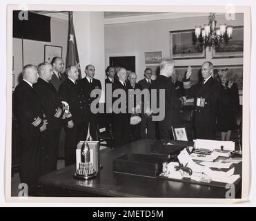 Coast Guard Commandant avanzato a pieno ammiraglio. Vice ammiraglio Russell R. Waesche, Comandante degli Stati Uniti Guardia costiera, è giurato come un ammiraglio pieno dall'Ammiraglio posteriore Thomas Gatch, avvocato generale del giudice degli Stati Uniti Navy, come la signora Waesche (estrema destra) e un gruppo di ufficiali di alto rango della Guardia Costiera guardare. La cerimonia si è svolta negli uffici del Segretario della Marina. Gli ufficiali della Guardia Costiera, da sinistra a destra, sono: L'ammiraglio posteriore Carl Michel; l'ammiraglio posteriore Joseph F. Farley; l'ammiraglio posteriore Charles A. Park; l'ammiraglio posteriore Lyndon Spencer; il comandante Willard J. Smith, l'aiutante del Comandante; posteriore Foto Stock