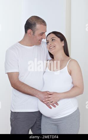 Donna incinta con partner, mano che tocca il ventre Foto Stock