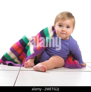 Bambina (12 mesi) con coperta colorata a strisce sulla spalla Foto Stock