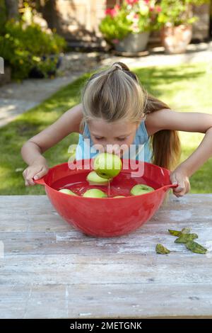 Ragazza che gioca apple bobbing gioco Foto Stock