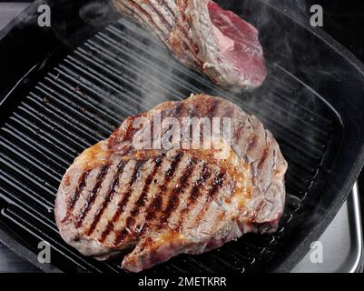 Girare la bistecca di manzo in una padella char-grill Foto Stock