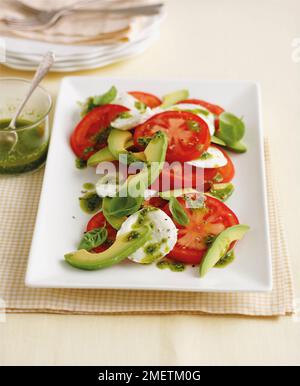 Insalata tricolore italiano con insalata di pomodori, avocadi, mozzarella, le foglie di basilico e pesto. Foto Stock