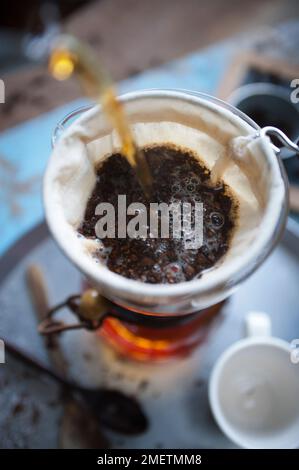 Caffe Touba, versando acqua calda nel caffè, scaricando attraverso un panno nella caraffa di vetro Foto Stock