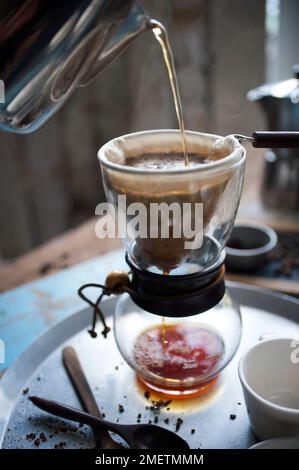 Caffe Touba, versando acqua calda nel caffè, scaricando attraverso un panno nella caraffa di vetro Foto Stock