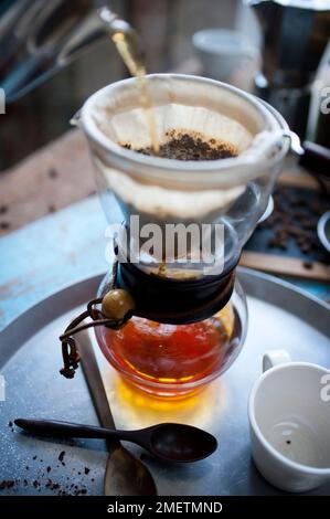 Caffè Touba, caffè che scorre attraverso un panno in una caraffa di vetro Foto Stock
