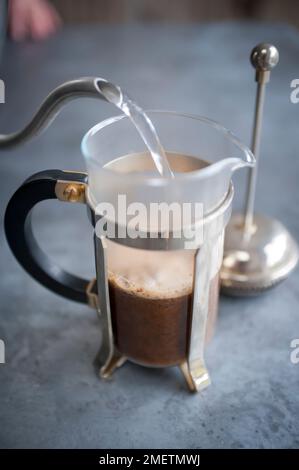 Versare acqua calda in una macchina da caffè a filtro Foto Stock