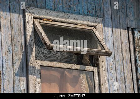 La finestra della vecchia casa in legno di legno sullo sfondo di pareti in legno. Foto Stock