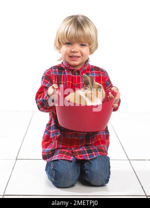 Giovane ragazzo seduto tenendo un coniglio in una vasca, 2 anni Foto Stock