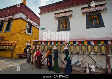Pellegrini tibetani, buddisti in costume tradizionale tibetano che circondano un piccolo tempio, Meru Ningba, ruote di preghiera, a Bakhor, vicino al tempio Jokhang Foto Stock