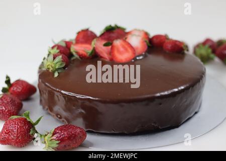 Torta al cioccolato con ganache e fragole fresche. Sparato su sfondo bianco con fragole fresche intorno. Foto Stock