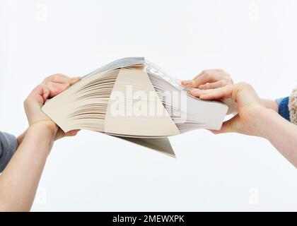 Bambini che cercano di tirare due libri con pagine interfogliate apart Foto Stock