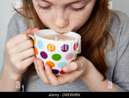 Bambino di bere una bevanda calda da un macchie mug Foto Stock