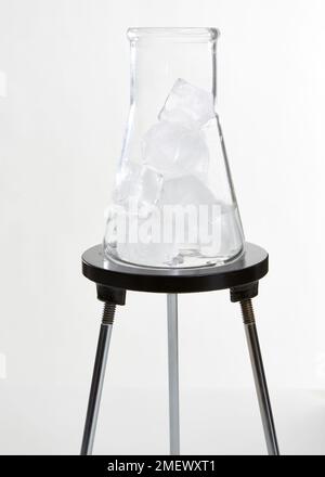 Vetro beuta conica su un treppiede contenente cubetti di ghiaccio Foto Stock