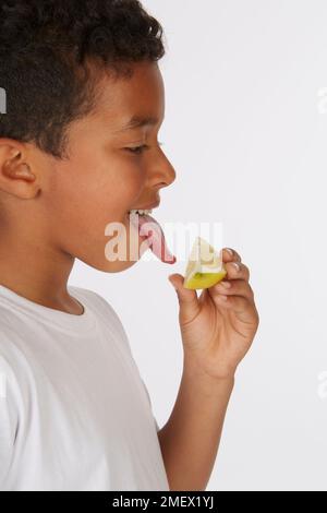 Un cuneo di limone è usato come parte di un test di gusto. Età del modello 8. Foto Stock