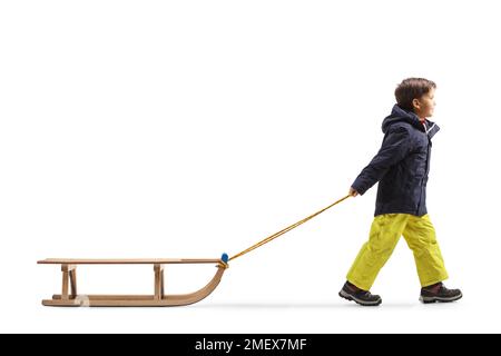 Foto a profilo intero di un ragazzo che tira una slitta di legno isolata su sfondo bianco Foto Stock