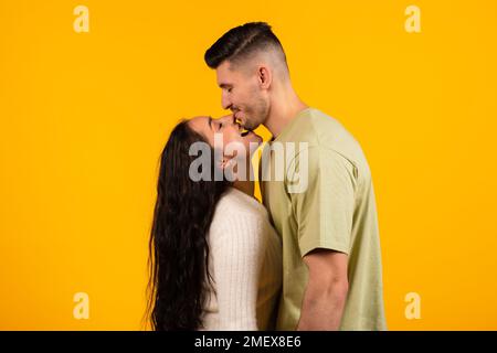 Felice sorridente moglie araba millenaria mordente alto marito in mento, coppia godere del tempo libero e divertirsi Foto Stock