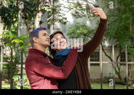 Due amici stanno prendendo selfie all'aperto. Ha capelli blu Foto Stock