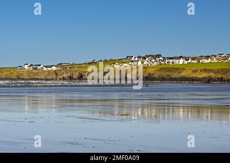 Poppit Sands, Cardigan, Galles - Marzo 2022: Sabbia bagnata sulla spiaggia con bassa marea, con Gwbert sul mare sullo sfondo. Sulla sinistra si trova il Cliff Hotel. Foto Stock