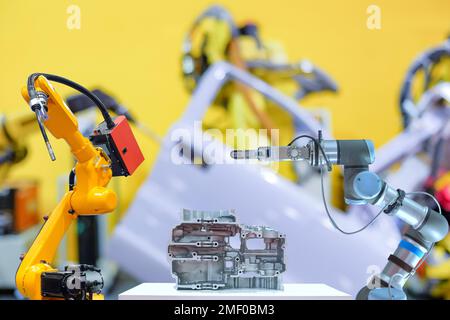 Robot industriale per saldatura e presa che lavora con parti metalliche su sfondo sfocato di fabbrica di smart car Foto Stock