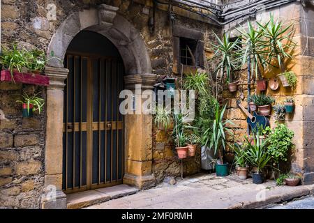 Porta d'ingresso di una casa medievale, decorata con verde e fiori, in una stradina nella città di Piazza Armerina. Foto Stock