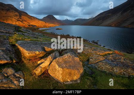 Spettacolare vista di Wastwater con nuvole scure e luce dorata sul paesaggio, Lake District, Regno Unito. Foto Stock