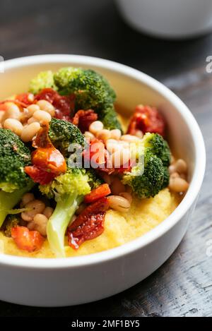 Broccoli e fagioli alla polenta con pomodori secchi e peperoni. Foto Stock