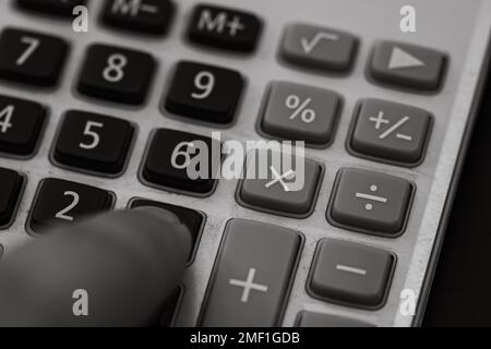 Premere con il dito il calcolatore dei pulsanti. Concetto fiscale, concetto contabile. L'uomo non riconoscibile tiene le mani e usa una calcolatrice Foto Stock