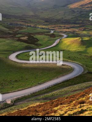 Lunga strada curva tortuosa che conduce attraverso la valle britannica sotto MAM Tor nel Peak District. Sfondi concettuali del paesaggio. Foto Stock