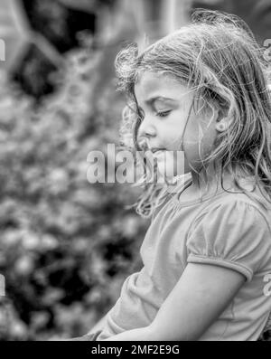 Foto laterale di una bambina all'aperto, in bianco e nero Foto Stock