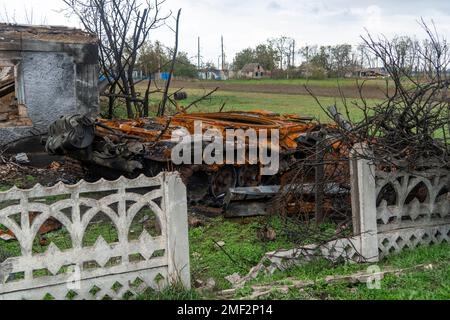 Campagna dopo battaglia. Distrutto bruciato battaglia serbatoio senza una torretta pistola si trova vicino a una casa distrutta. Guerra in Ucraina. Invasione russa dell'Ucraina Foto Stock